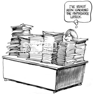 B&W business cartoon showing a female worker at her desk filled with stacks and stacks of paper. She is thinking, 'I've really been ignoring the paperwork, lately'.