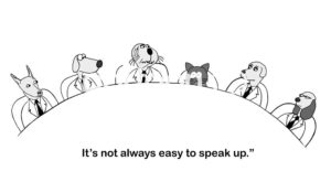 Office b&w cartoon of a meeting with five dogs and one cat, "It's not always easy to speak up".