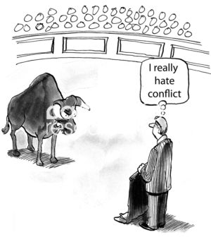 B&W conflict cartoon showing a businessman in the bullfighting ring with a bull about to attack.  He thinks, 'I really hate conflict'.