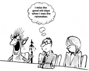 B&W sales cartoon showing a salesman who wishes he was still the company sales rainmaker, instead the crazy guy sitting beside him is the new company rainmaker. 