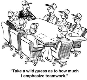 Teamwork cartoon showing a team meeting where everyone is wearing a sports team cap.  The male, team leader says, "take a wild guess as to how much I emphasize teamwork".