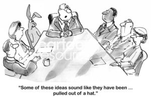 B&W business cartoon of people at a team meeting including a rabbit. The boss says, 'some of these ideas sound like they have been ..... pulled out of a hat'.