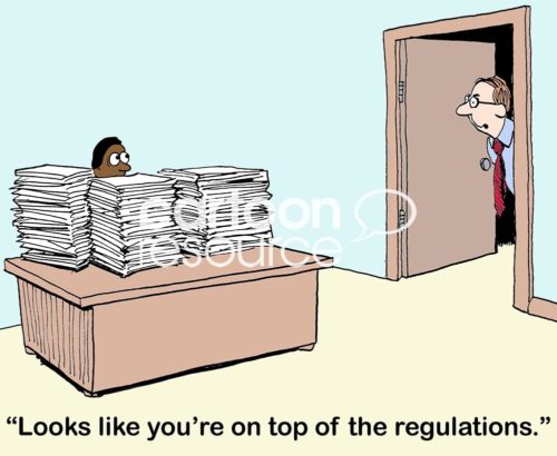 Color office cartoon showing an African-American worker man sitting at a desk filled with stacks of papers. His boss looks in his office and says, 'Looks like you're on top of the regulations'.