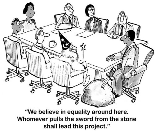 B&W office cartoon showing a meeting with seven people of diverse type and a large stone with a sword stuck in it. The meeting leader states, 'we believe in equality around here. Whomever pulls the sword from the stone shall lead this project'.